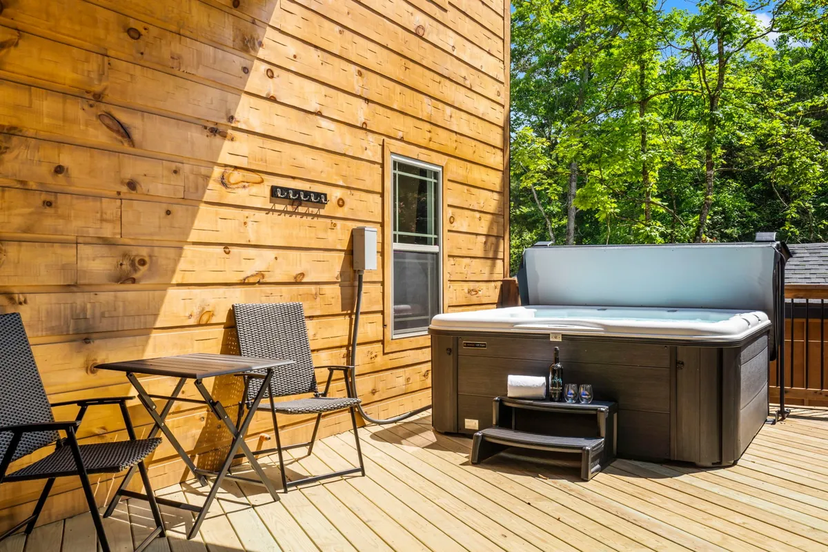 This exterior image features a private hot tub set against a wooden wall, with outdoor seating inviting guests to relax. The space is perfect for unwinding after a day of exploring, with ample room for small groups to gather and enjoy drinks or conversation under the open sky.