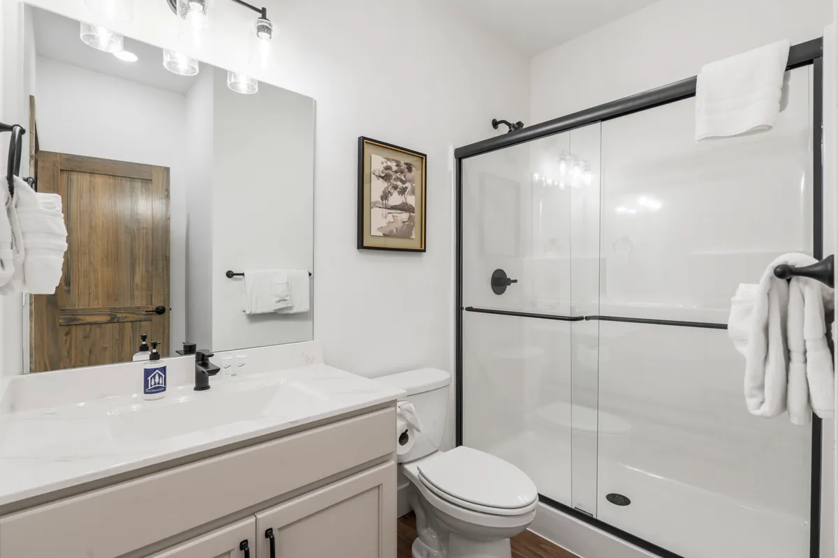 A sparkling, modern bathroom with a sink, shower, mirror, and stylish framed artwork. The space feels clean and refreshing, perfect for morning routines or winding down at night.