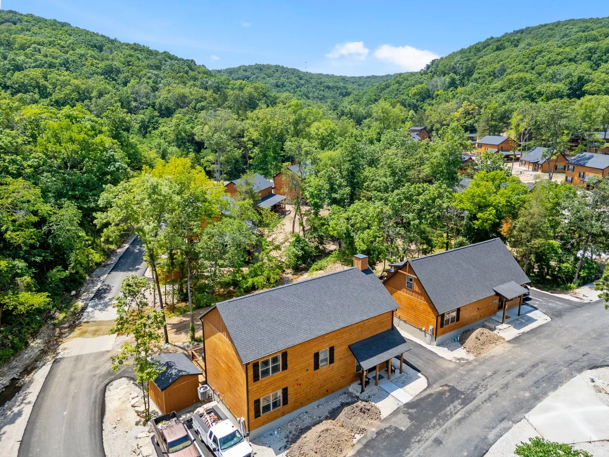 This image displays several charming wooden cabins surrounded by greenery, with a winding road leading through the area. The setting highlights the proximity of nature and the availability of trails for hiking or family walks. The mood is peaceful and rejuvenating, making it ideal for showcasing outdoor activities.