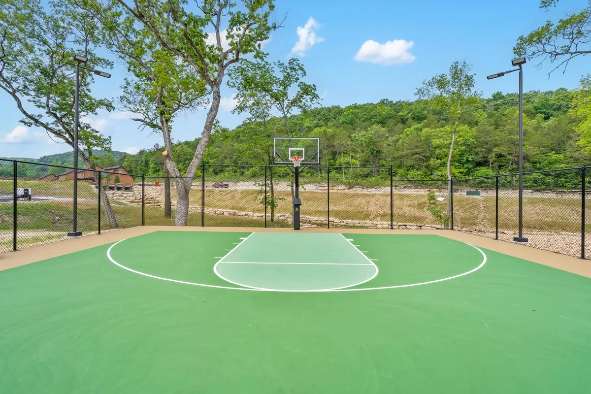 This vibrant exterior image showcases a basketball court framed by tall trees, creating an energetic and active setting for friendly competitions and social play among groups. The open court is ready for games and shared memories.