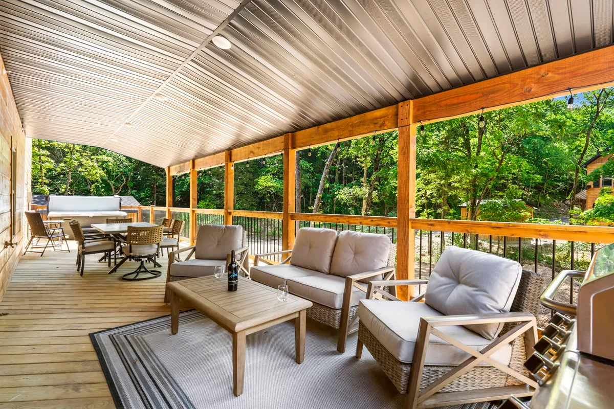 A spacious outdoor deck featuring a comfortable seating area and a dining table, set against a backdrop of lush natural greenery. The arrangement suggests leisurely gatherings or tranquil solo moments, and the deck overlooks a peaceful, wooded landscape that feels both private and inviting.